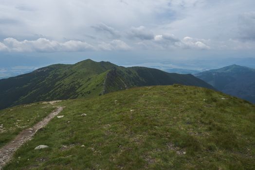 View from Banikov peak on Western Tatra mountains or Rohace panorama. Sharp green mountains - ostry rohac, placlive and volovec with hiking trail on ridge. Summer blue sky white clouds