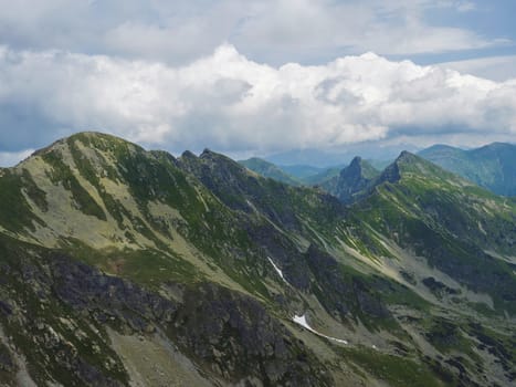 View from Banikov peak on Western Tatra mountains or Rohace panorama. Sharp green mountains - ostry rohac, placlive and volovec with hiking trail on ridge. Summer blue sky white clouds