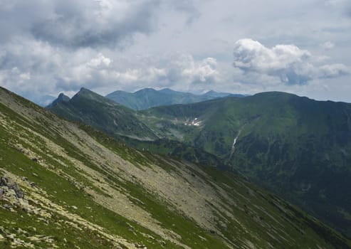 View from Banikov peak on Western Tatra mountains ridge or Rohace panorama. Sharp green mountains - ostry rohac and placlive peak. Summer blue sky white clouds