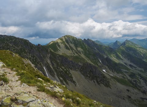 View from Banikov peak on Western Tatra mountains or Rohace panorama. Sharp green mountains - ostry rohac, placlive and volovec with hiking trail on ridge. Summer blue sky white clouds