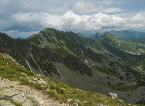 View from Banikov peak on Western Tatra mountains or Rohace panorama. Sharp green mountains - ostry rohac, placlive and volovec with hiking trail on ridge. Summer blue sky white clouds