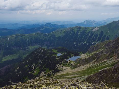 view from Banikov peak on Western Tatra mountains or Rohace panorama. Sharp green mountains ostry rohac, placlive and volovec and mountain lake Rohacska plesa. Summer blue sky white clouds
