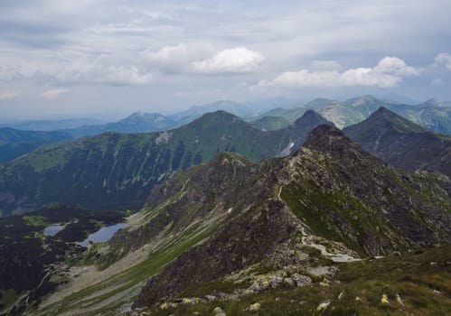View from Banikov peak on Western Tatra mountains or Rohace panorama. Sharp green mountains - ostry rohac, placlive and volovec with hiking trail on ridge. Slovakia. Summer blue sky white clouds.