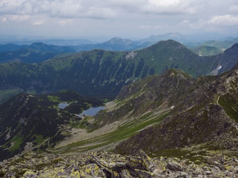 View from Banikov peak on Western Tatra mountains or Rohace panorama. Sharp green mountains - ostry rohac, placlive and volovec with hiking trail on ridge. Slovakia. Summer blue sky white clouds.