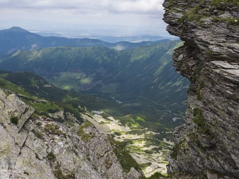 Beautiful vivid blue mountain lake Rohacske pleso with green mountain peaks and hiking path. view from the Ostry rohac, Western Tatras mountains, Rohace Slovakia, summer sunny day blue sky.