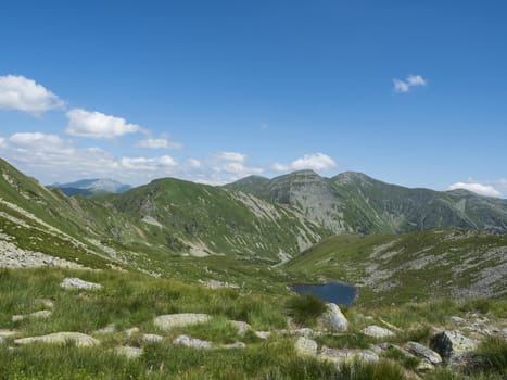 Beautiful vivid blue mountain lake Horne Jamnicke pleso with green mountain peaks view from the Jamnice sedlo saddle, Western Tatras mountains, Rohace, Slovakia, summer sunny day blue sky