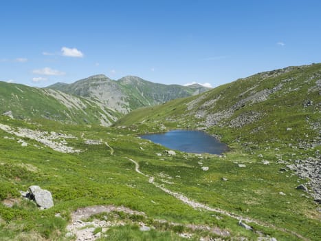 Beautiful vivid blue mountain lake Horne Jamnicke pleso with green mountain peaks view from the Jamnice sedlo saddle, Western Tatras mountains, Rohace, Slovakia, summer sunny day blue sky