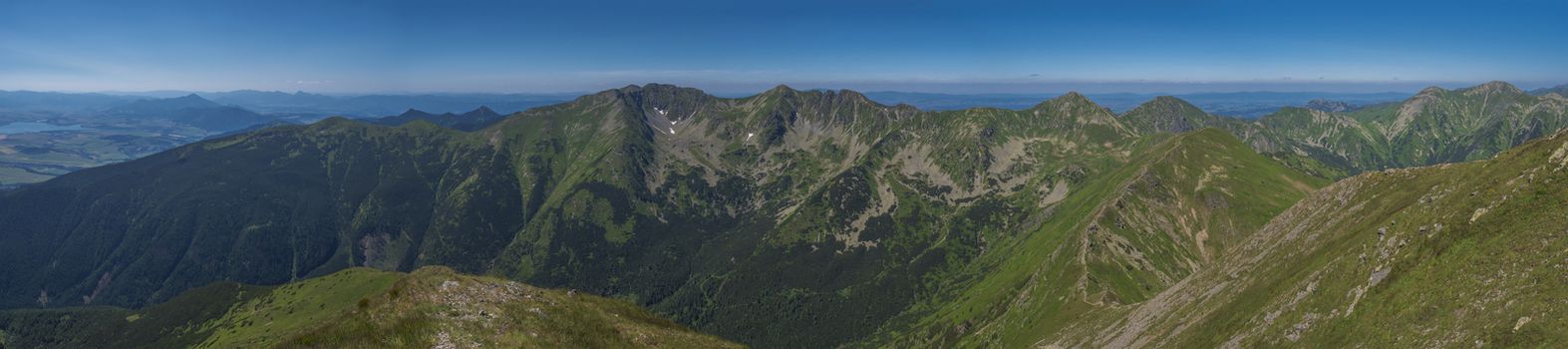 Panoramic view from Baranec peak on Western Tatra mountains Rohace, high tatras and low tatras panorama. Sharp green mountain peaks with hiking trail on ridge. Summer, blue sky white clouds