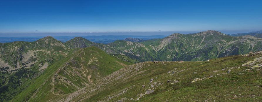 Panoramic view from Baranec peak on Western Tatra mountains Rohace, high tatras and low tatras panorama. Sharp green mountain peaks with hiking trail on ridge. Summer, blue sky white clouds