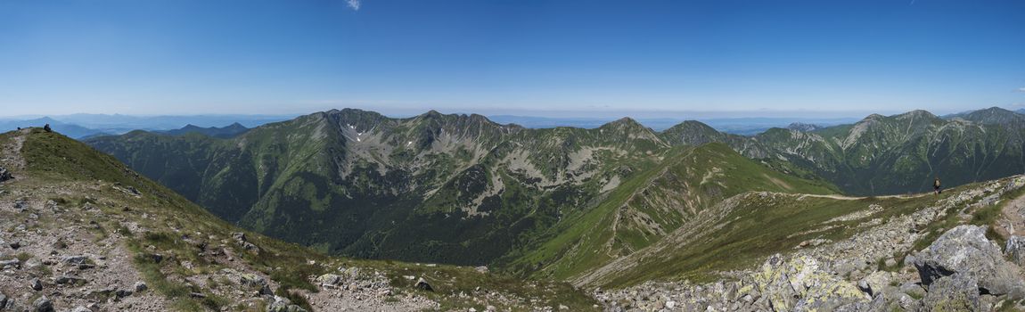 Panoramic view from Baranec peak on Western Tatra mountains Rohace, high tatras and low tatras panorama. Sharp green mountain peaks with hiking trail on ridge. Summer, blue sky white clouds