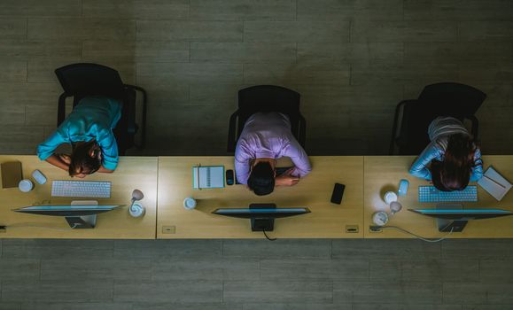 Top view of Three Asian customer care service working hard late and sleeping in night shift at office,call center department,worker and overtime,team work with colleagues for success concept