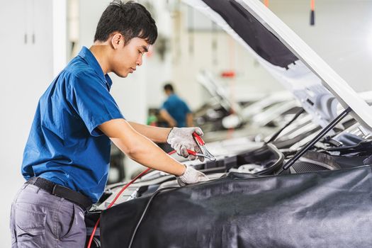 Asian mechanic Checking and repairing the car in maintainance service center which is a part of showroom, technician or engineer professional work for customer, car repair concept