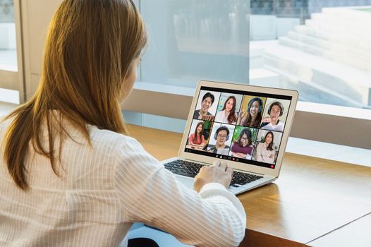 Rear View of Asian Business woman meeting with teamwork colleague sharing and presenting in video conference when Coronavirus outbreak, Covid-19 pandemic,remote online meeting and new normal concept