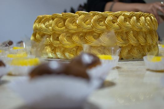 Golden birthday cake covered in chantilly with sweeties on the foreground