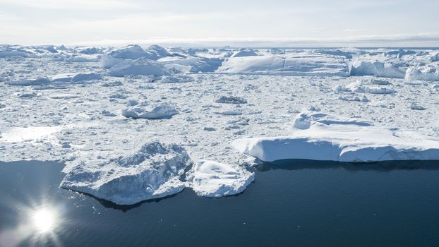 Iceberg aerial drone image - Global warming and climate change concept. Giant icebergs in Disko Bay on greenland in Ilulissat icefjord from melting glacier Sermeq Kujalleq Glacier, Jakobhavns Glacier.