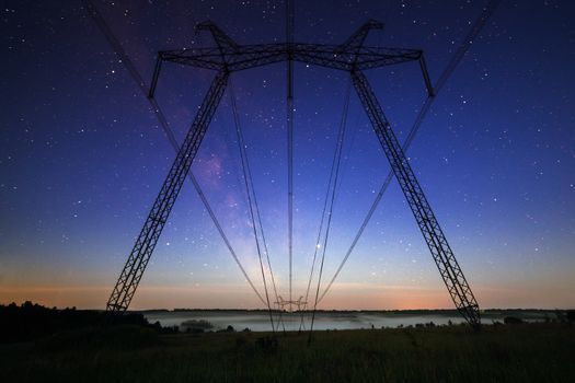 huge power line towers on field at summer evening.