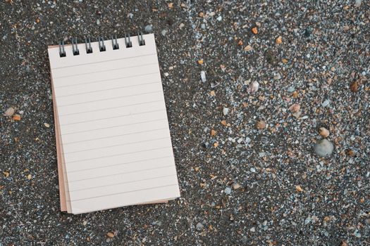 Small white notebook on sand at beautiful beach sea texture background.