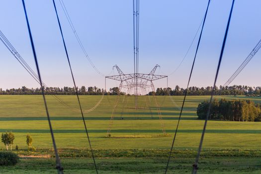 huge power line towers on field at summer evening.