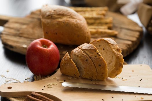 French bread baguette cut on wooden board with knife. with a chocolate butter and red apple.