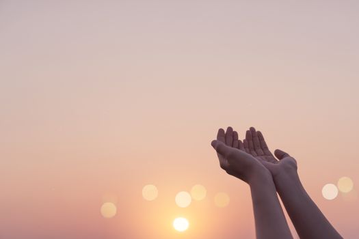 Woman hands place together like praying in front of nature blur beach sunset sky background.