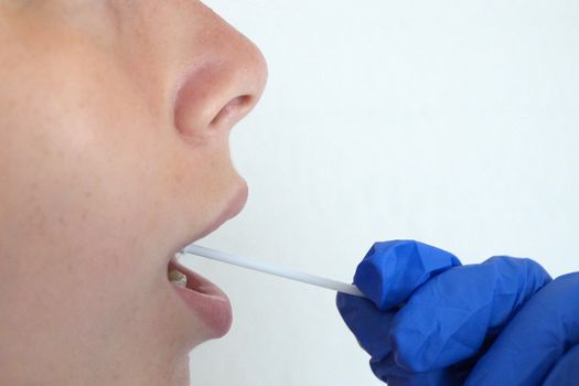 the doctor takes a test for coronavirus from the girl's mouth.