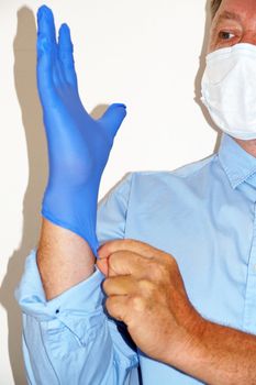masked doctor puts on medical gloves close up