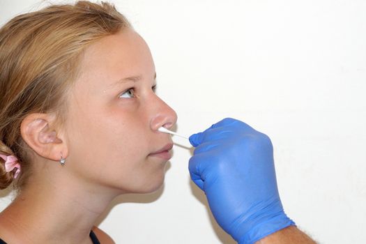 the doctor takes a test for coronavirus from the girl's nose.