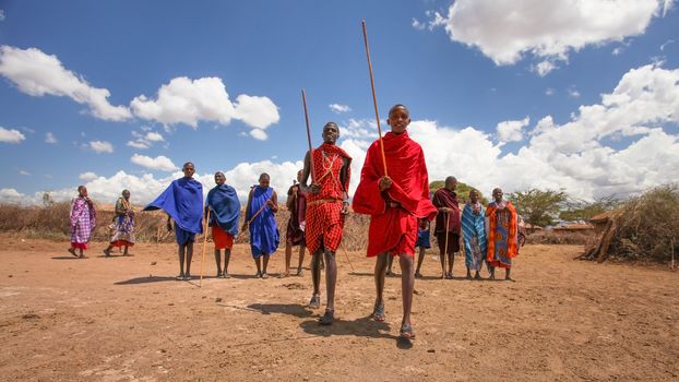 Unknown Masai village near Amboselli park, Kenya - April 02, 2015: Masai warriors lining up for traditional dancing and singing with deep blue sky in background