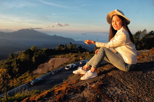 Happy woman siting on green grass meadow on top of mountain and enjoying nature ,sunrise in winter

