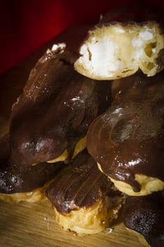 Eclairs with chocolate icing on a wooden table