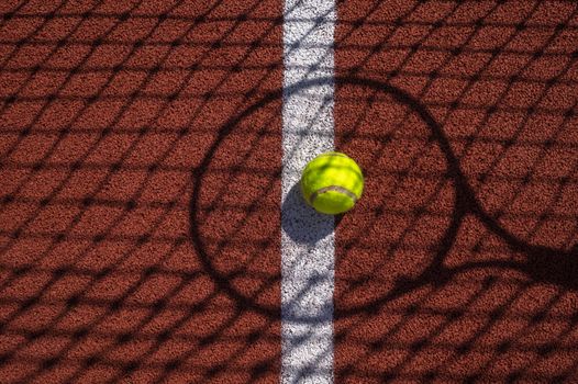 Shadows of net and racket surrounding a tennis ball on a white line on an outdoor court in sunshine in a sport and active lifestyle concept