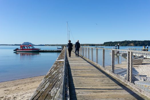 Tauranga New Zealand - July 27 2020; Omokoroa waterfront with two people walking away on the pier.
