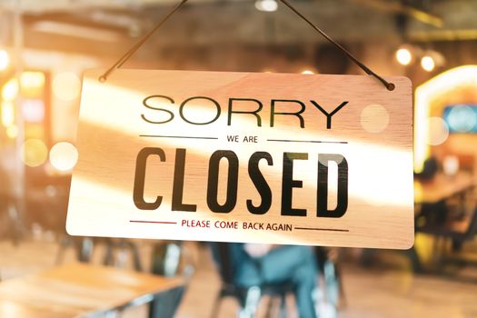 A Sign board of sorry we are closed hang on door of business shop background.