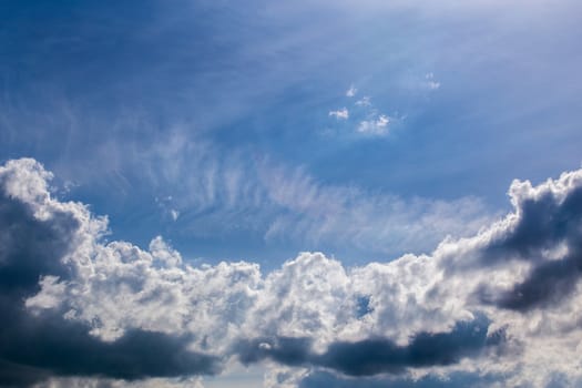 distant backlit cumulus and feather clouds near horizon closeup telephoto shot with polarizing effect