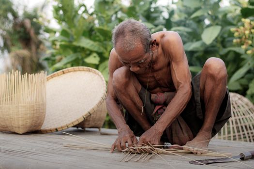 Oldman in the countryside are weaving basket of Thailand.