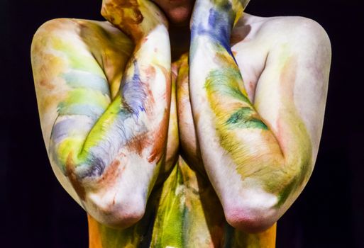 Chest of a girl with her nipples covered in her hands. Body art. Drawing on the body. Beautiful girl with painted body watercolors. A white young girl painted the body with paint.