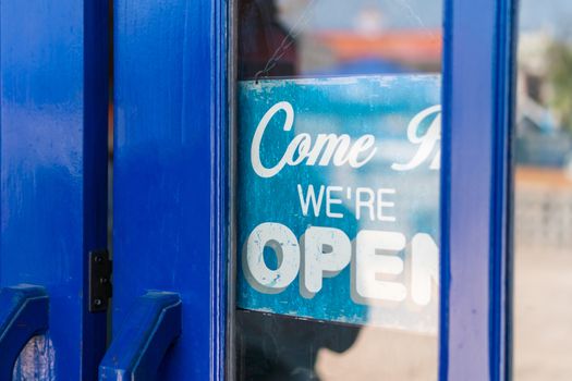 A business sign that says open on cafe or restaurant hang on door at entrance. Vintage color tone style.