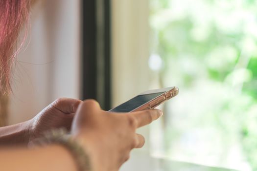 Woman hand use smartphone to do work business, social network, communication in public cafe work space area.