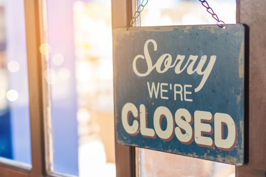 A Sign board of sorry we are closed hang on door of business shop with nature green background