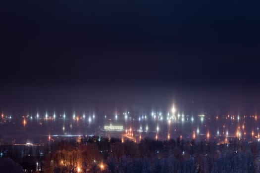night winter cityscape with light pillars atmospheric phenomenon.