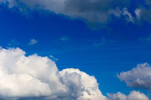 Regular spring clouds on blue sky at daylight in continental europe. Close shot wit telephoto lens and circular polarizing filter.