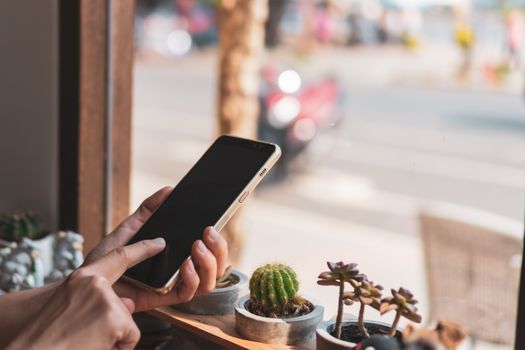 Woman hand use smartphone to do work business, social network, communication in public cafe work space area.