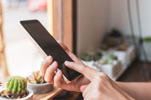 Woman hand use smartphone to do work business, social network, communication in public cafe work space area.