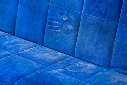 dusty blue sofa surface with palm prints closeup with selective focus.