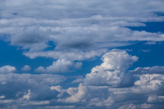 Regular spring clouds on blue sky at daylight in continental europe. Shot wit telehoto lens and circular polarizing filter.