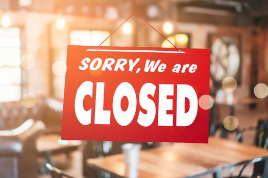 A Sign board of sorry we are closed hang on door of business shop background.