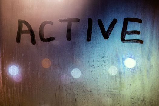 the word active written on night wet window glass close-up with bokeh background.