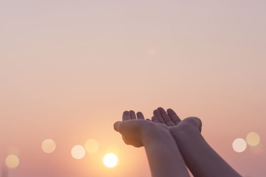 Woman hands place together like praying in front of nature blur beach sunset sky background.