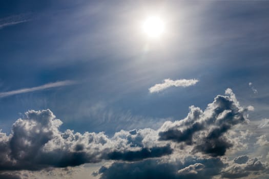 distant misty backlit cumulus and feather clouds near horizon closeup telephoto shot with sun