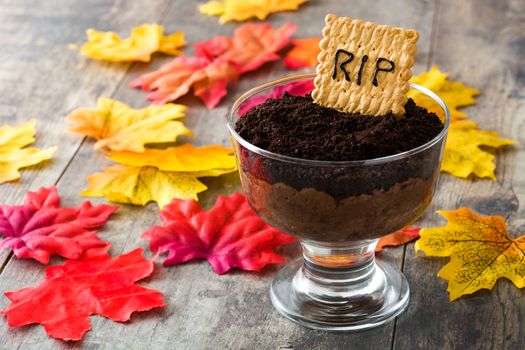 Funny Halloween chocolate mousse with tomb cookie on wooden table